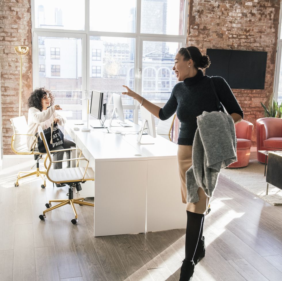 woman waving goodbye to colleague in office