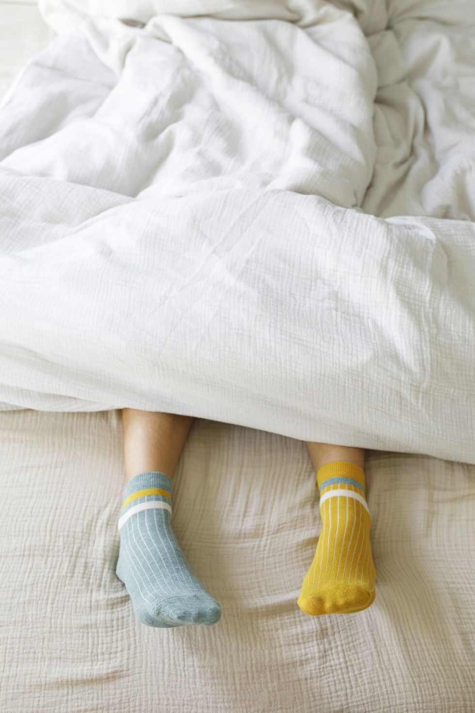 woman wearing blue and yellow socks in bed