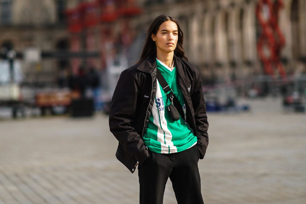 paris, france march 09 a model wears a a black jacket, a green and white stripe v neck soccer t shirt, a mini fanny pack bag crossbody, black pants, on march 09, 2021 in paris, france photo by edward berthelotgetty images