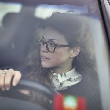 woman wearing glasses steering her car