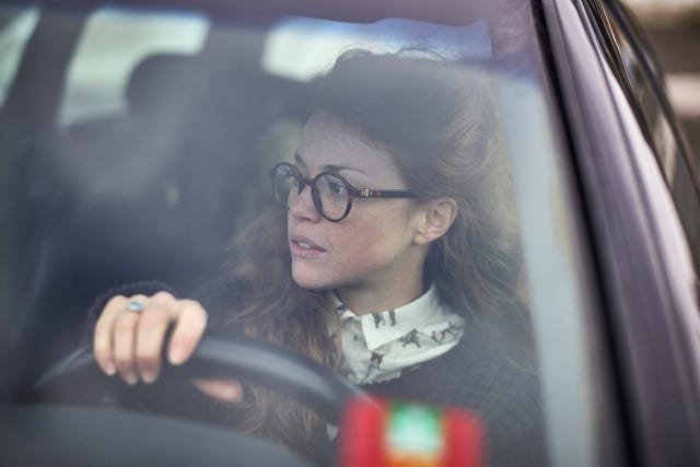 woman wearing glasses steering her car