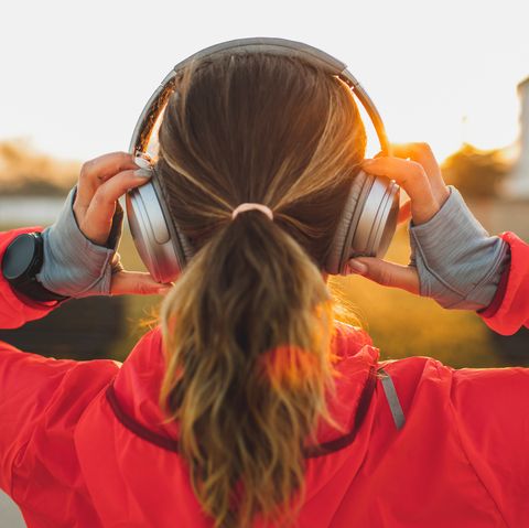 woman wearing headphones and listening music on morning run view from behind