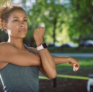 woman wearing smart watch stretching at park