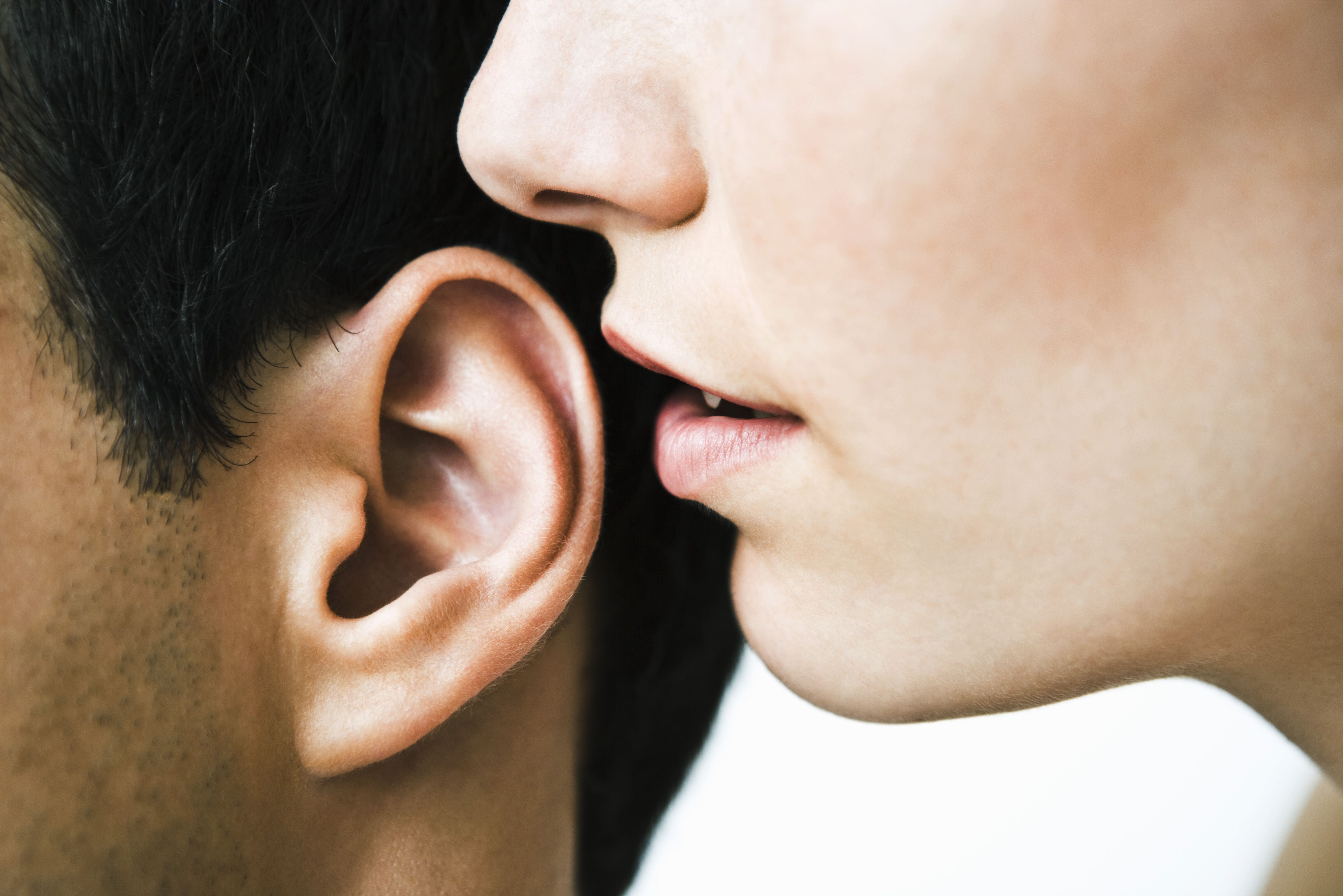 woman whispering in man's ear, close up