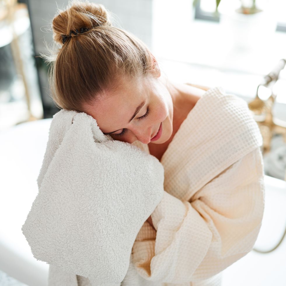 woman wipes face with a towel after taking a bath