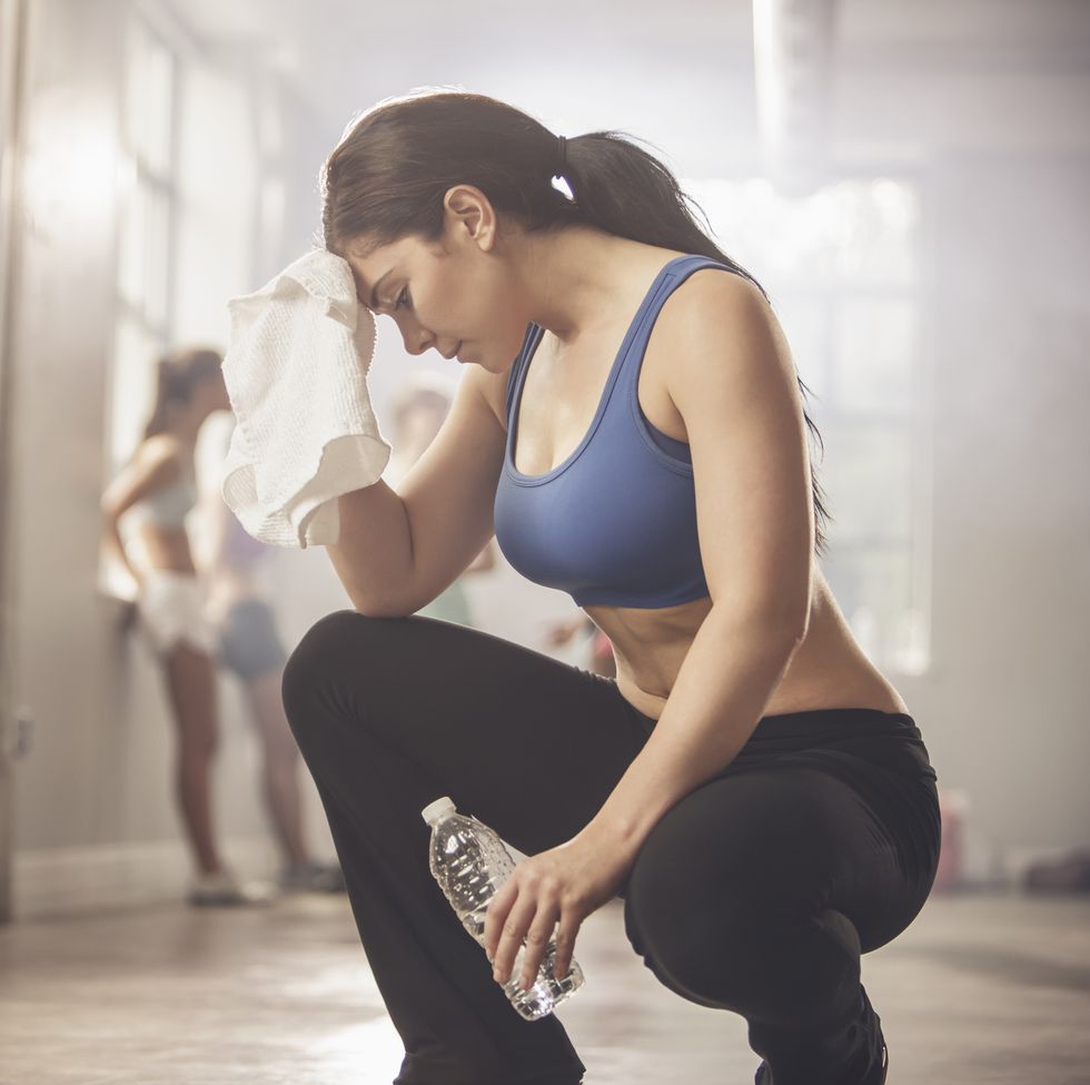 woman wiping sweat with towel in gym