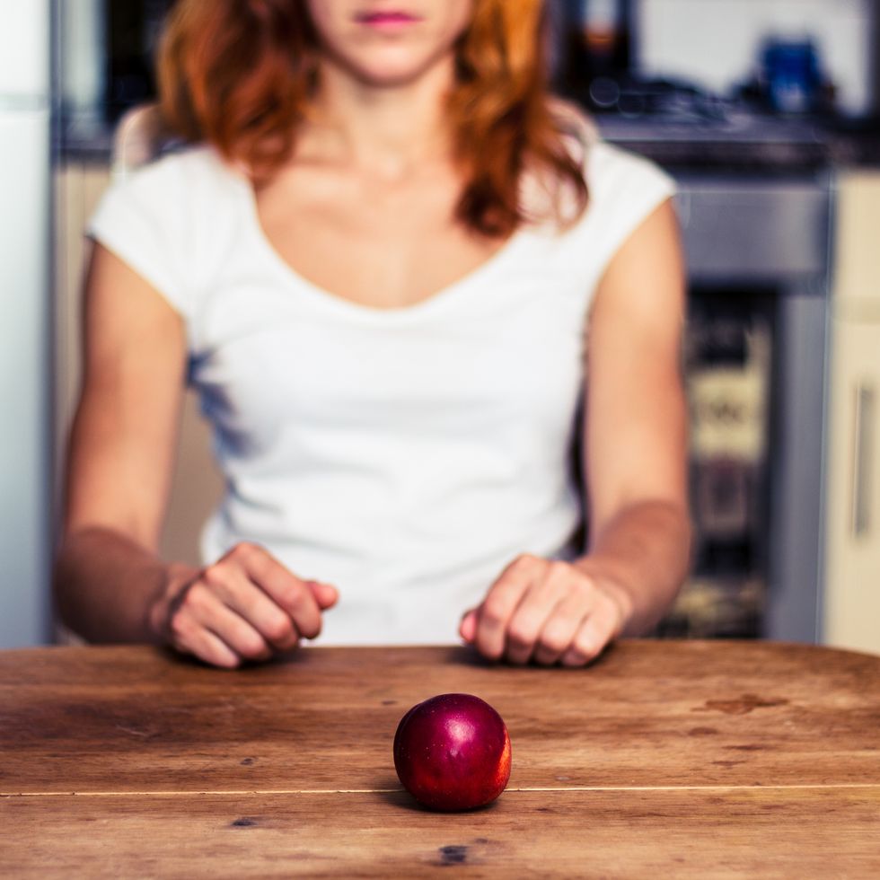 Woman with a nectarine in kitchen