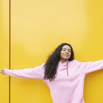 Woman with arms outstretched against yellow background