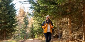 woman with backpack hiking on footpath in forest at spring