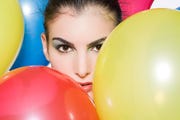 face of woman with red, blue and yellow balloons and staticky hair