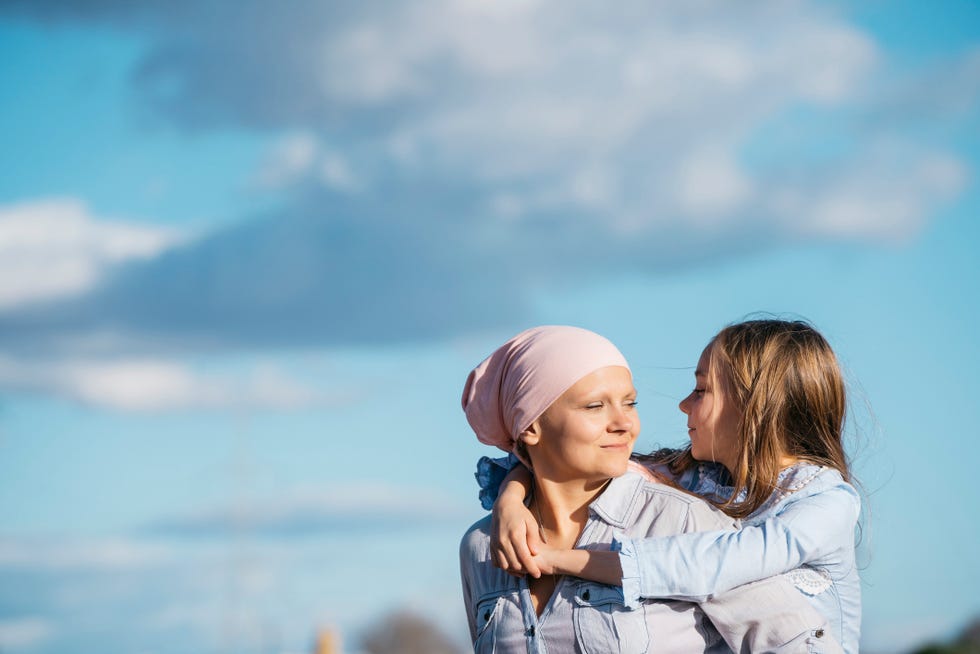 a woman with cancer is next to her daughter a girl is hugging a woman happy
