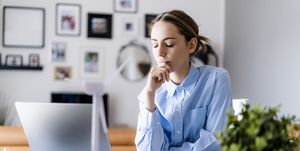 Woman with closed eyes in office with wind turbine model on table