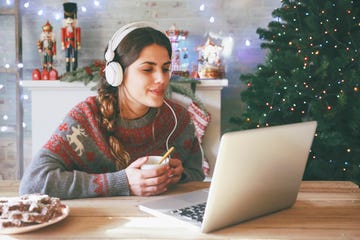 woman with cup of coffee using laptop and headphones at christmas time