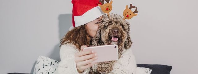 Woman With Dog Taking Selfie On Bed At Home