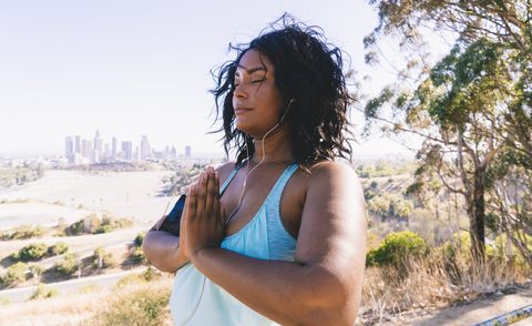 woman with eyes closed doing prayer position exercise against clear sky
