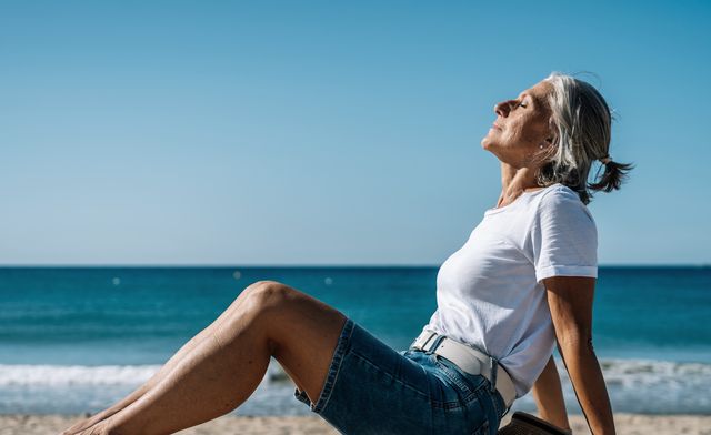 mujer tomando el sol sentada en muro