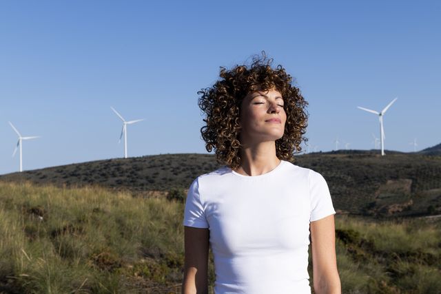 mujer con los ojos cerrados delante de turbinas de viento