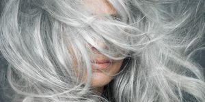 Woman with grey hair blowing across her face.