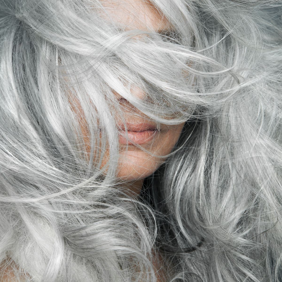 https://hips.hearstapps.com/hmg-prod/images/woman-with-grey-hair-blowing-across-her-face-royalty-free-image-1597686931.jpg?crop=0.66635xw:1xh;center,top&resize=1200:*