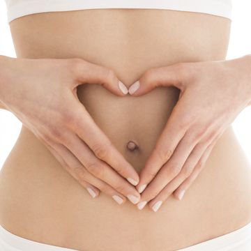 woman with hands in heart shape on tummy