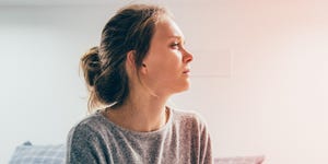 woman with hands on stomach suffering from pain, looking aside