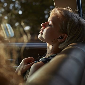 woman with headphones relaxing in car, at sunset