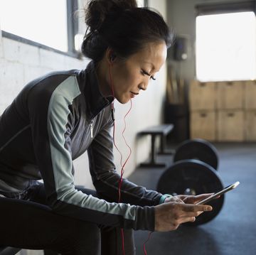 Woman with headphones using cell phone at gym