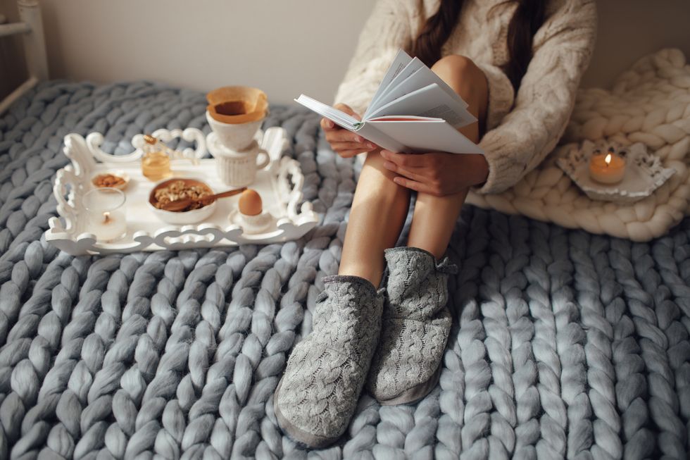 暖かい寝具の上で読書するロングヘアの女性