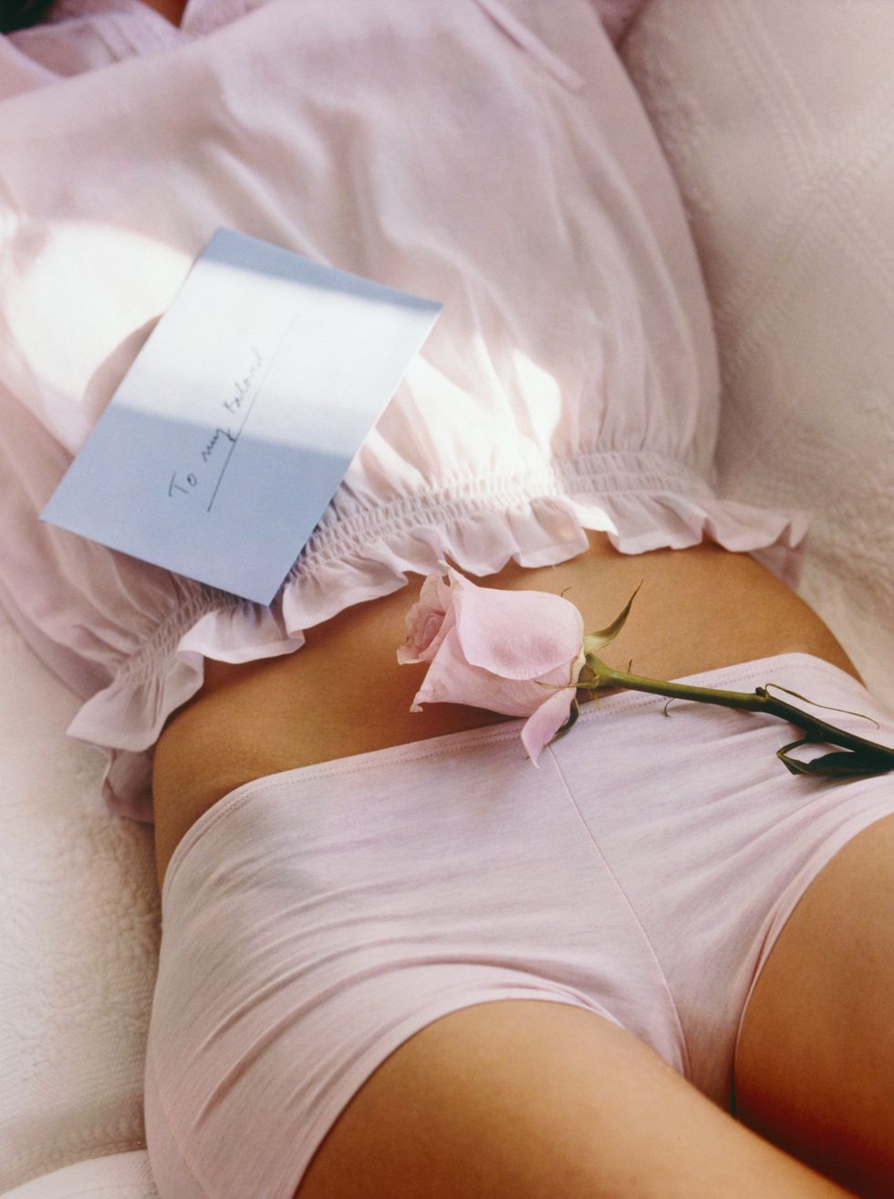 woman with love letter and rose on her stomach