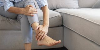 woman with ms holding ankle in pain