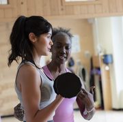 woman with personal trainer lifting weights in gym