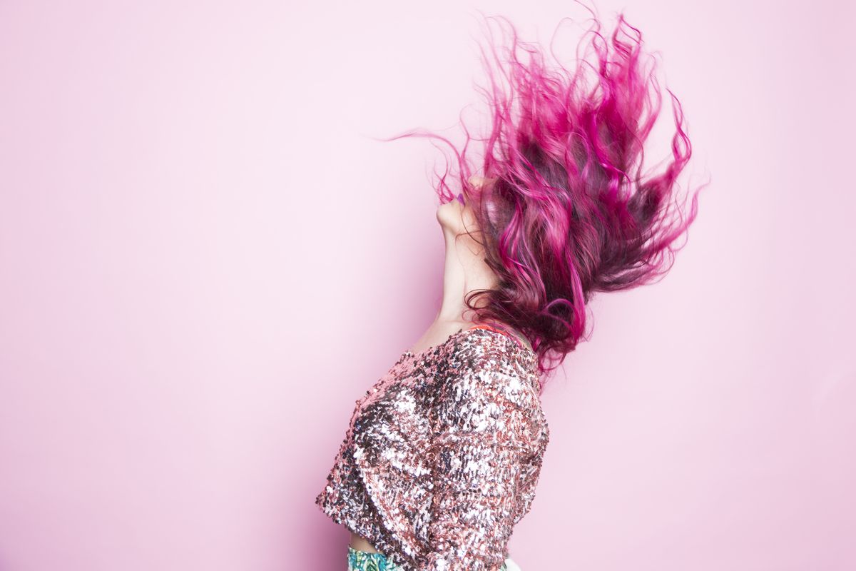 a woman with pink hair throws her head back