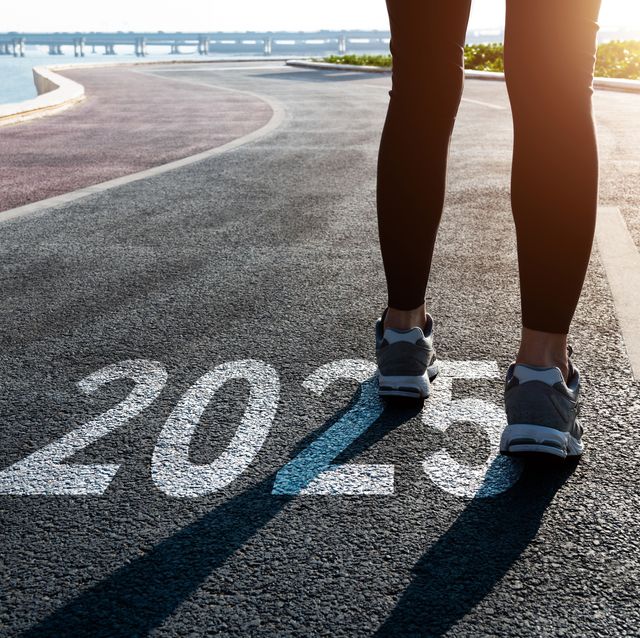 woman with running shoes standing and number 2025 on road