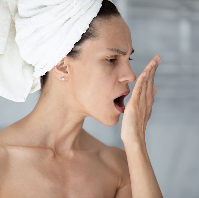 woman with towel on head opens mouth check breath