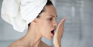 woman with towel on head opens mouth check breath