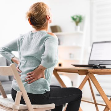 woman working on a laptop and having back, hip, spine pain