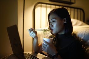 woman working on her laptop in her bedroom at night