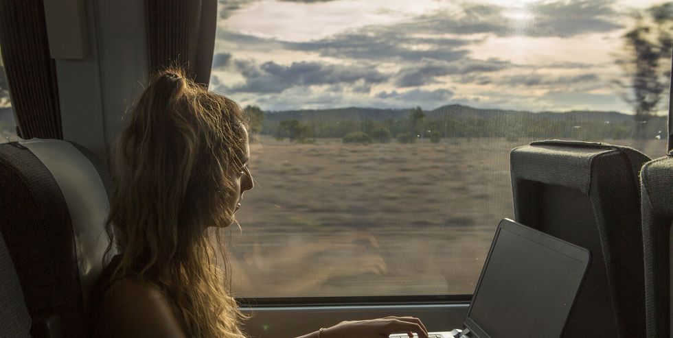 a woman works on her laptop while traveling on a train
