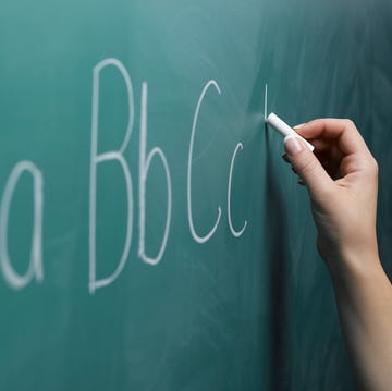 Woman writing alphabet on chalkboard, close-up