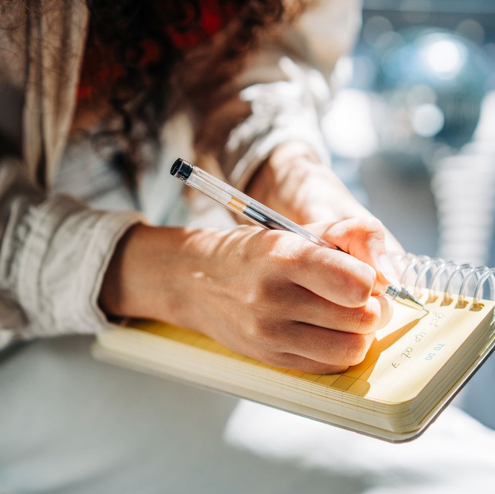 woman writing in her notebook, making a to do list.