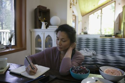 Woman writing in journal in living room