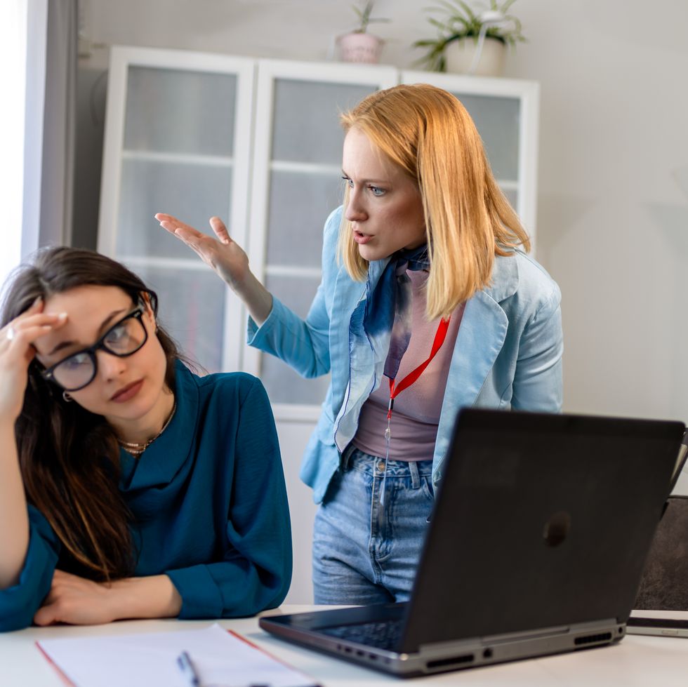 woman yelling at a colleague in an office, showing workplace bullying.