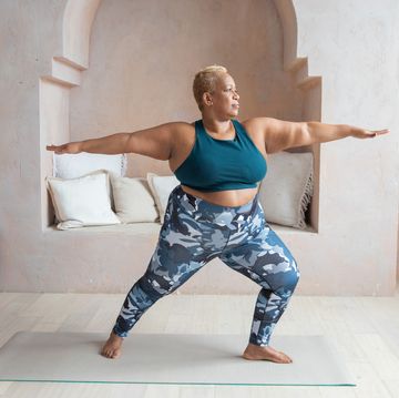 an older black woman doing yoga and demonstrating the warrior two pose in a studio