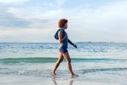 young female walking on a quiet beach barefoot