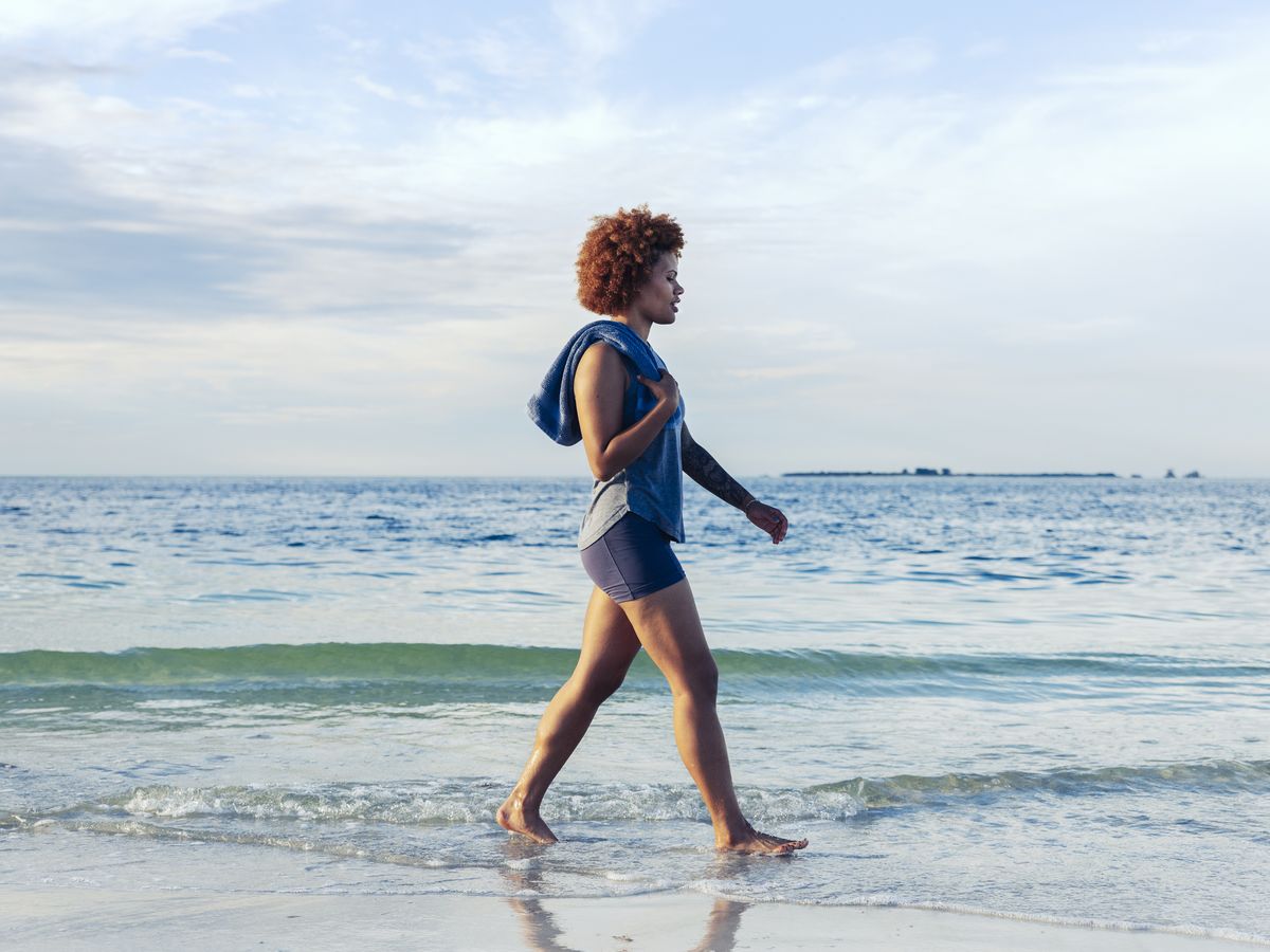 Girl With Loose Hair Walks In Sea. Attractive Young Woman In Blue