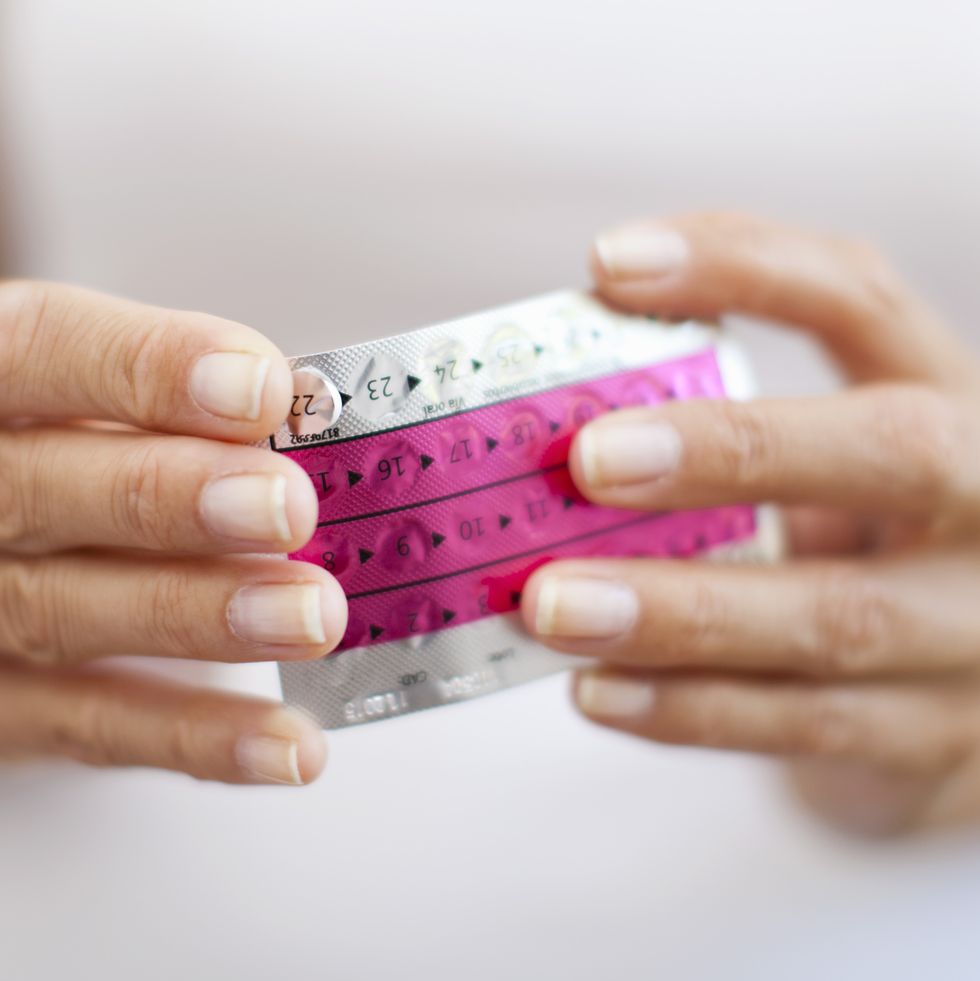 Woman's hand holding birth control pills, cropped