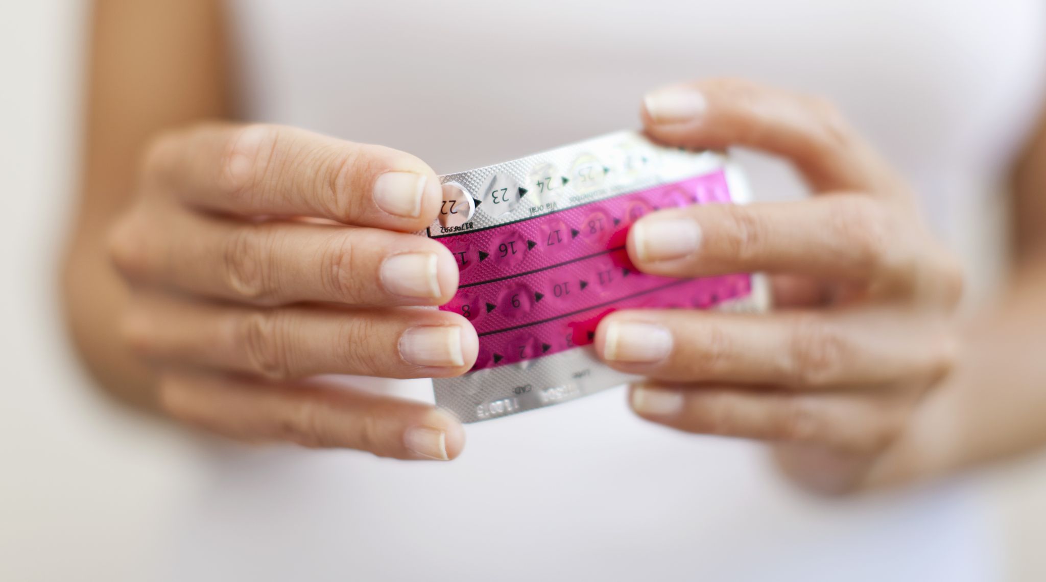 woman's hand holding birth control pills, cropped