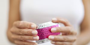 woman's hand holding birth control pills, cropped