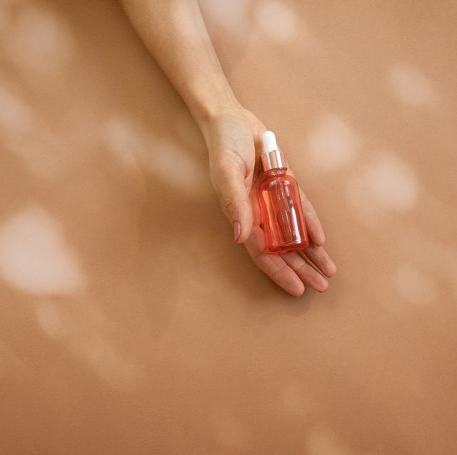 woman hand holding glass bottle with cosmetic liquid