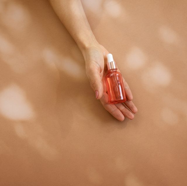 woman hand holding glass bottle with cosmetic liquid